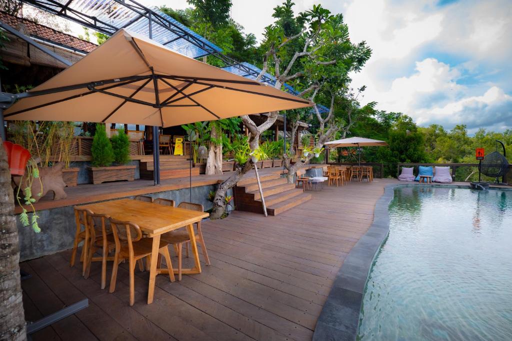 patio con tavolo e ombrellone accanto alla piscina di Arkamaya Kusuma Resort a Yogyakarta