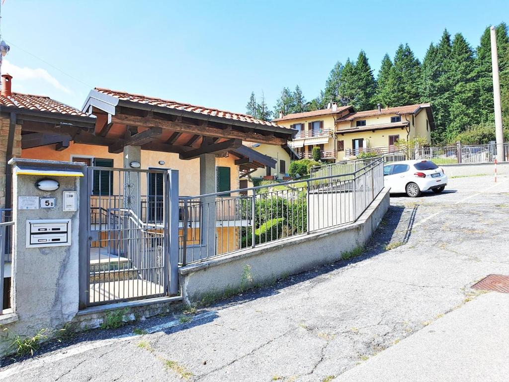 a fence in front of a house with a car at Apartment in Bosco with Scenic Terrace in Montegrino Valtravaglia