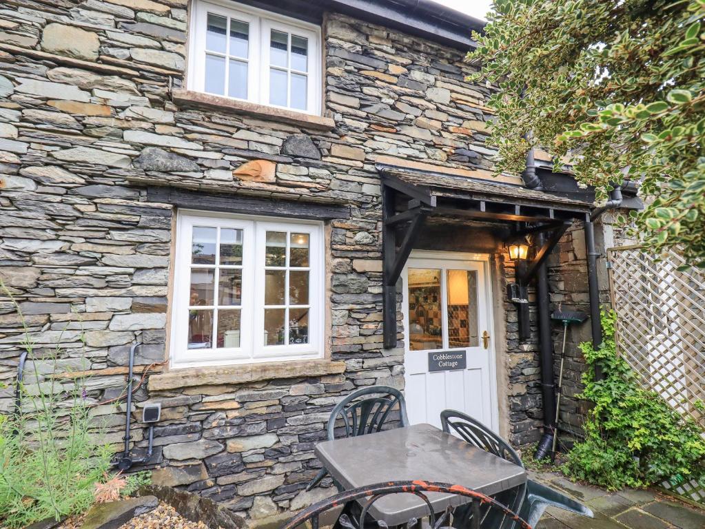 a stone cottage with a table in front of it at Cobblestone Cottage in Ambleside