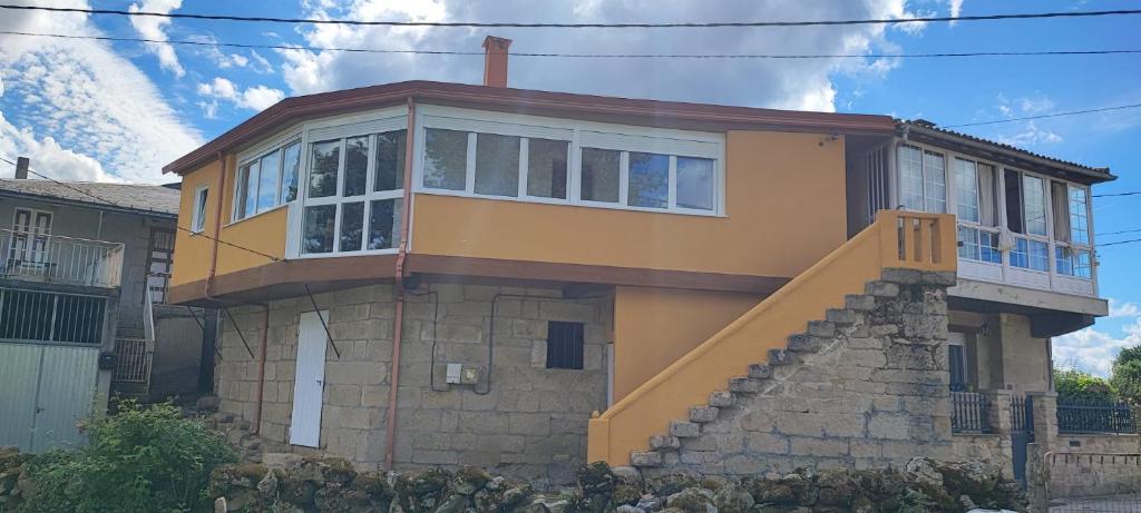 a yellow house with a staircase in front of it at Casa do Outeiro de Aguil in Castro Caldelas