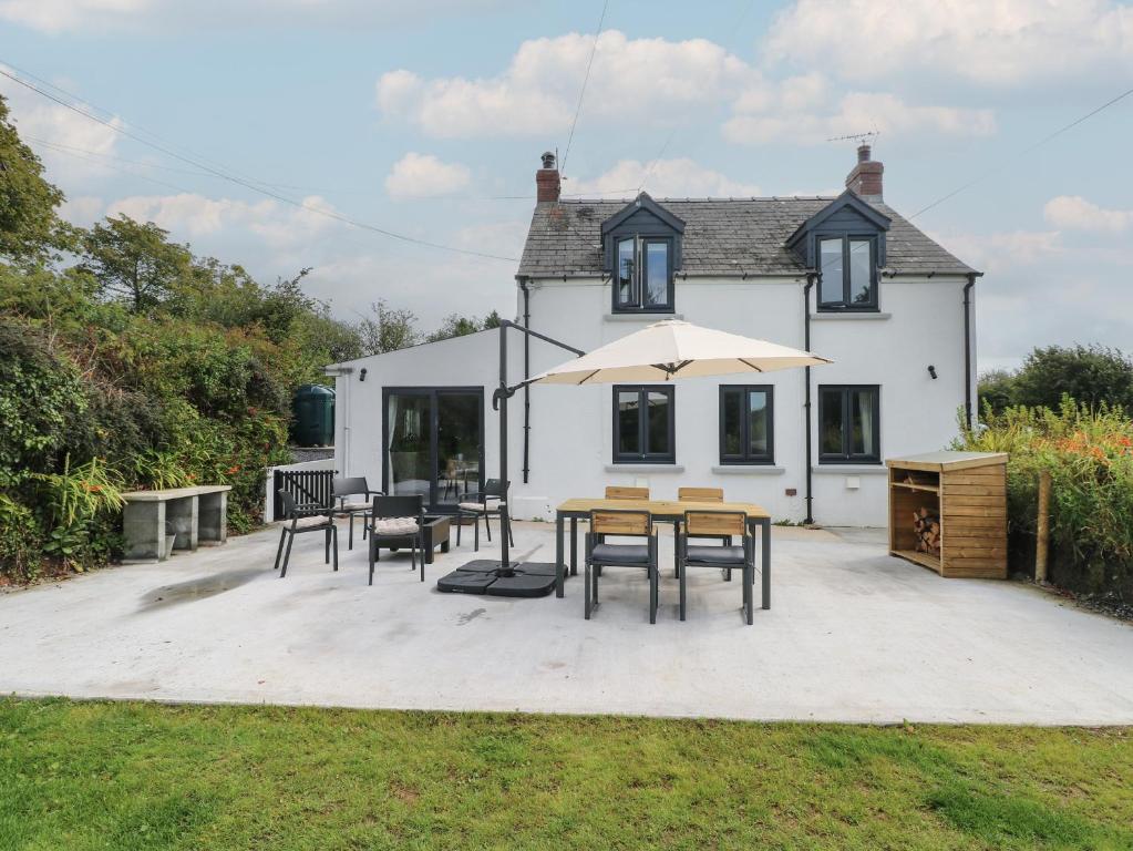ein Haus mit einem Tisch und Stühlen und einem Sonnenschirm in der Unterkunft Folly Cottage in Narberth