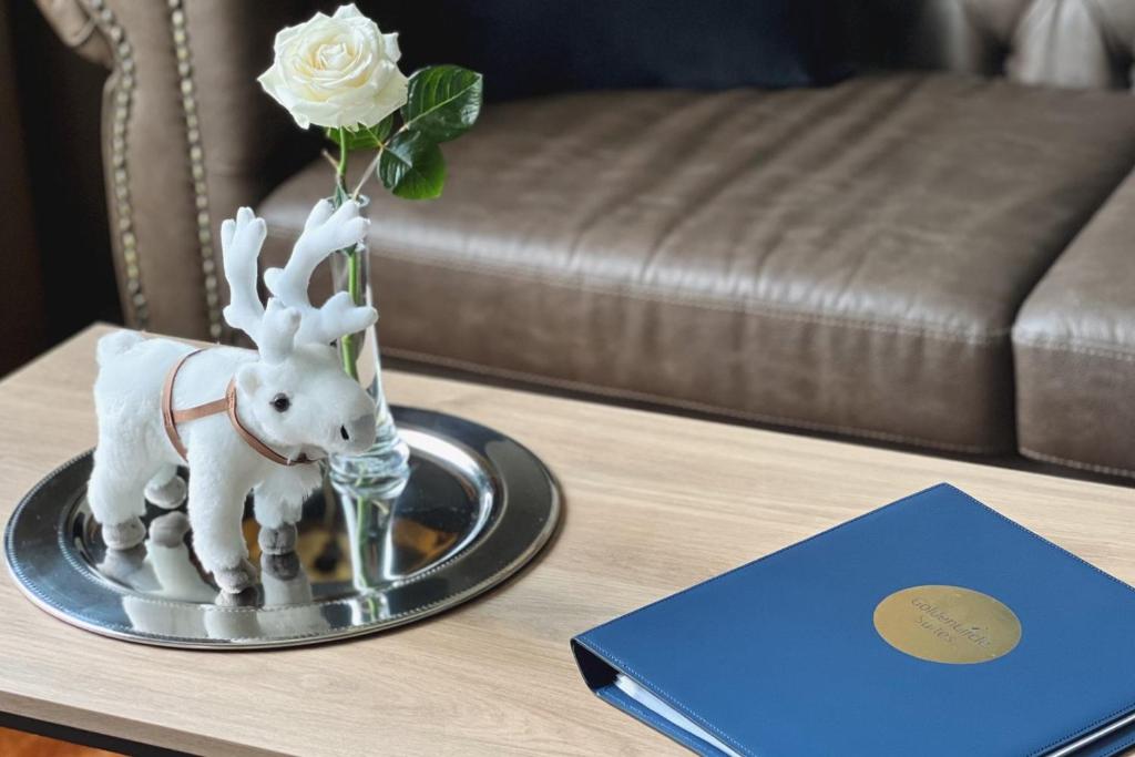 a vase with a flower on a table next to a book at Hotel Golden Circle Suites in Rovaniemi