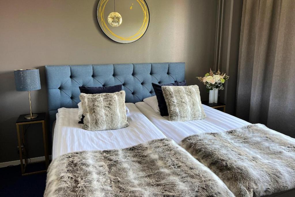 a bedroom with a bed with a blue headboard and pillows at Hotel Golden Circle Suites in Rovaniemi