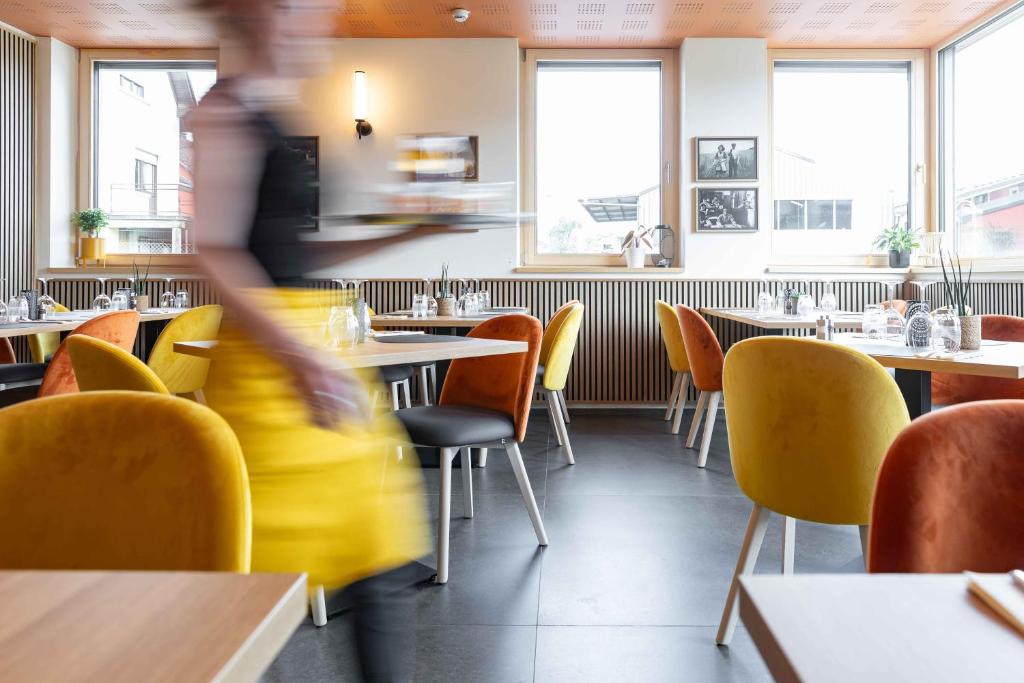 a person walking through a restaurant with tables and chairs at La Différence in Vichten