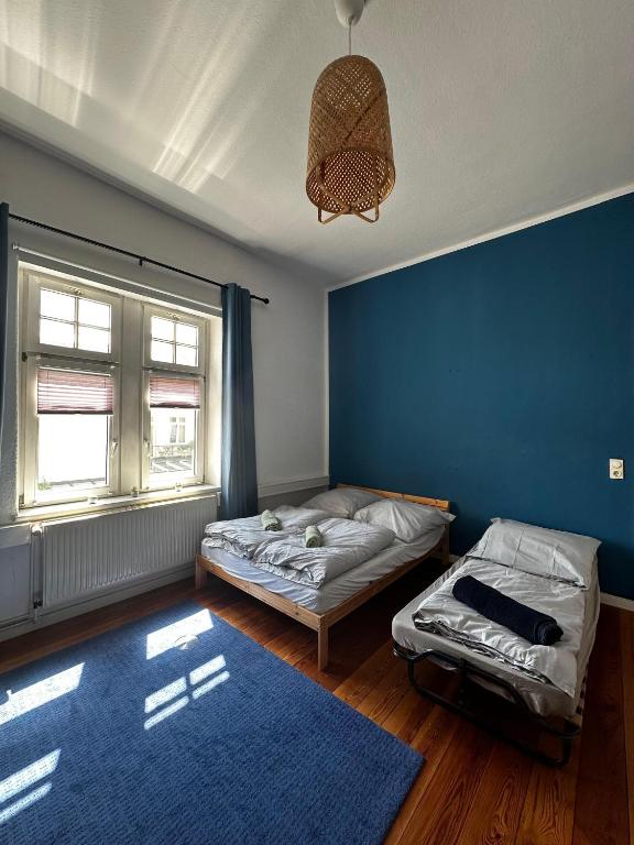 a bedroom with two beds and a blue wall at Unterkunft Mozart Magdeburg in Magdeburg