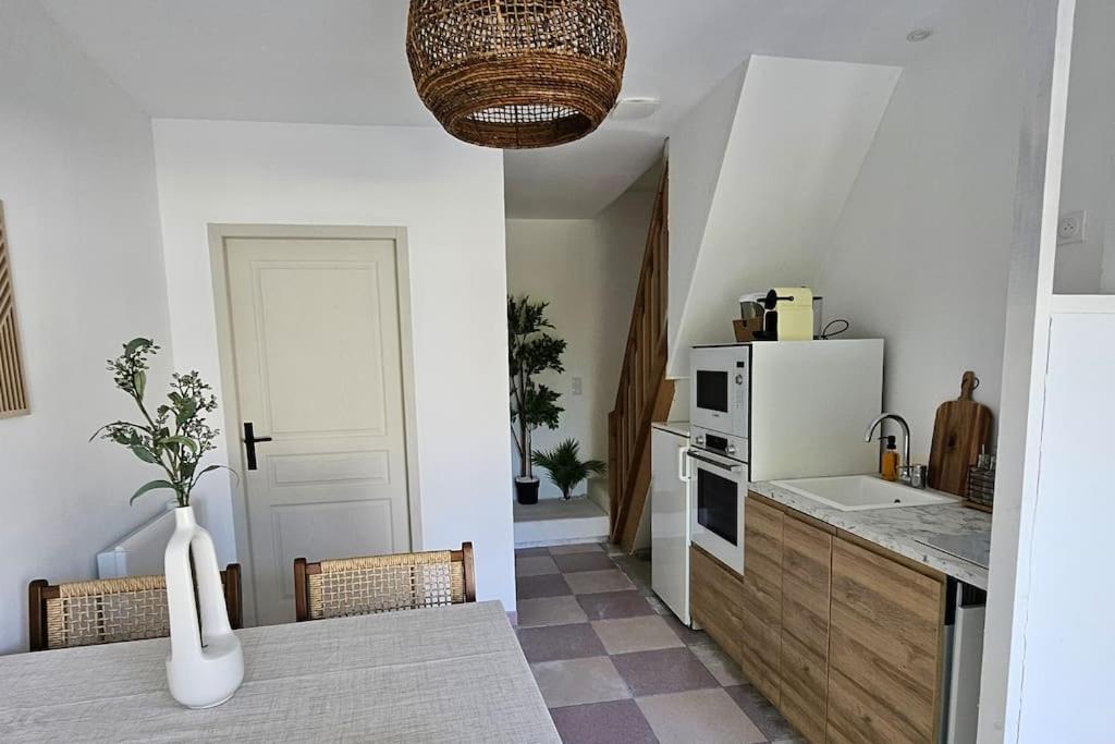 une cuisine avec une table et un réfrigérateur blanc dans l'établissement Sejour détente en bord de mer au gîte des falaises, à Plouha