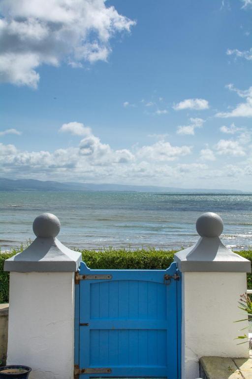 a blue gate with a view of the ocean at Llety in Criccieth