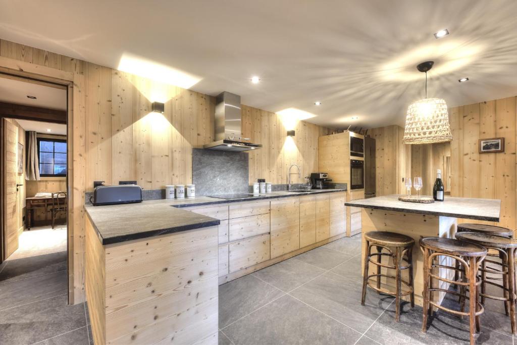 une grande cuisine avec des placards en bois et des tabourets de bar dans l'établissement Picherie bas - 10Pax - Calme - Vue montagne, à Saint-Gervais-les-Bains