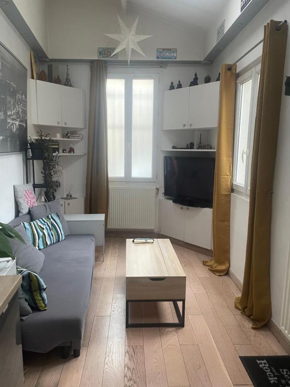 Una sala de estar con un sofá y una mesa de café. en Appartement Cosy tout équipé, en Colombes