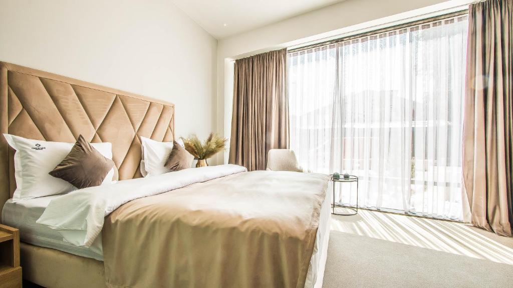 a bedroom with a large bed with a large window at Central Apart Hotel in Bucharest