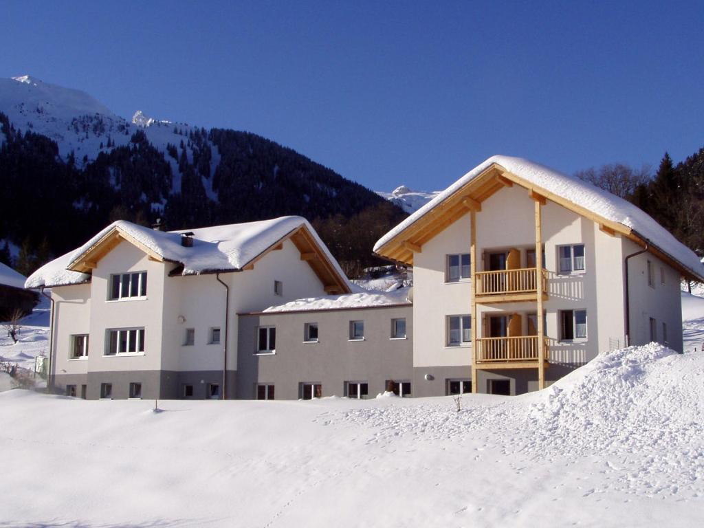 twee gebouwen in de sneeuw met een berg op de achtergrond bij Gästehaus Hausberger in Schruns