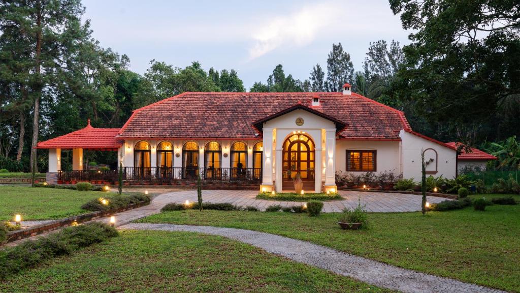 une maison avec un toit rouge et une cour dans l'établissement SaffronStays Biccode Woodside Heritage, à Belūr
