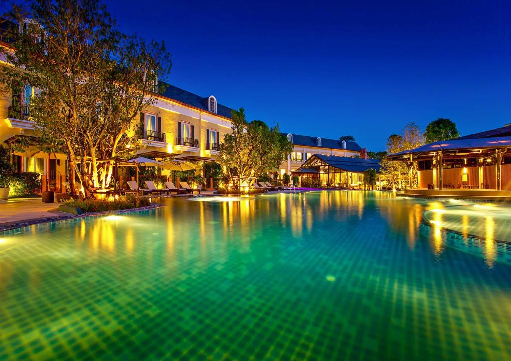 a large swimming pool in front of buildings at night at Rancho Charnvee Resort & Country Club Khaoyai in Pak Chong