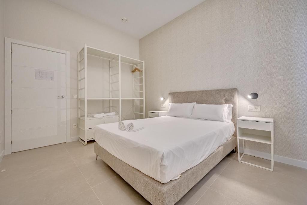 a bedroom with a large white bed and a bathroom at Apartamentos Panda by Clabao in Pamplona