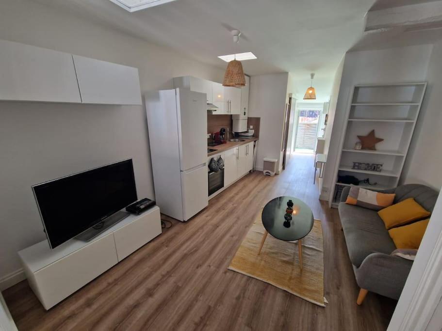 un salon avec une télévision, un canapé et une table dans l'établissement Charmant T2 proche de la Gare Matabiau, à Toulouse