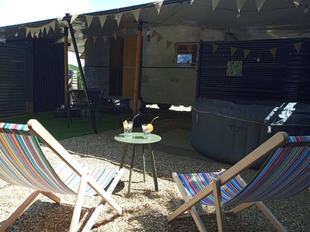 deux chaises et une table devant une tente dans l'établissement Caravane vintage avec spa, à Saint-Aignan