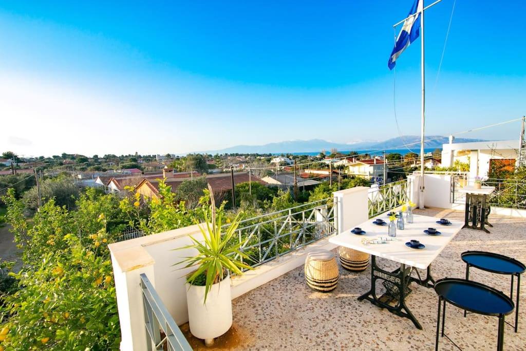 a patio with a table and chairs on a balcony at Kalamos sea view villa Beach walking distance in Áyioi Apóstoloi
