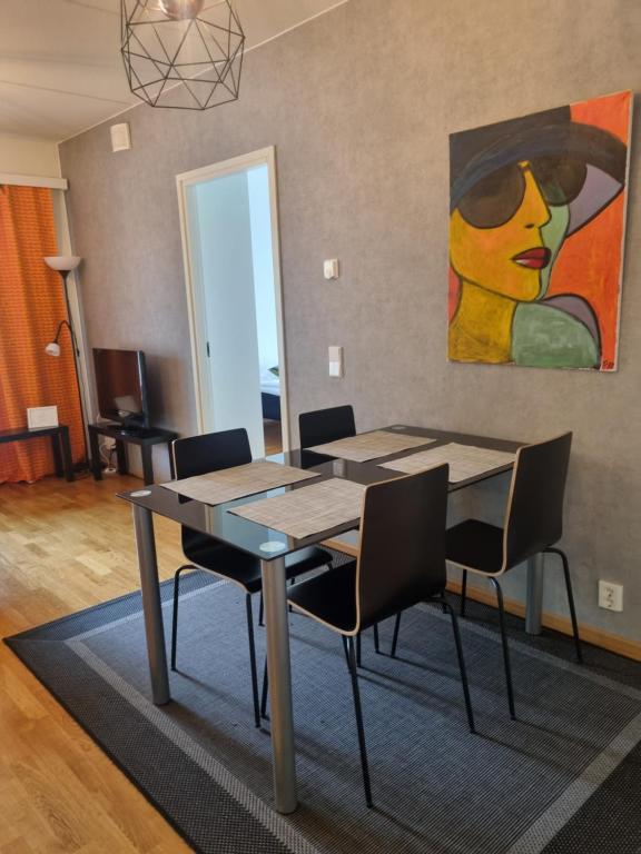 a dining room table with chairs and a painting on the wall at Wanha Neuvola Apartment in Pieksamaki