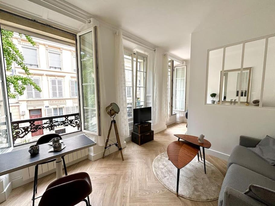 un salon avec un canapé et quelques fenêtres dans l'établissement Studio Châtivesle, à Reims