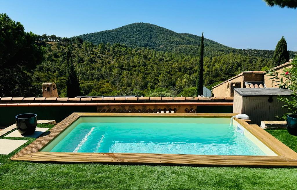 une piscine dans l'herbe avec une montagne en arrière-plan dans l'établissement Maison avec piscine privative près de la mer, à La Londe-les-Maures
