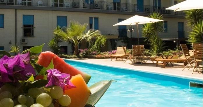 una piscina con un mazzo di frutta e fiori accanto a un hotel di Hotel Villa Giusy a Castellaneta Marina