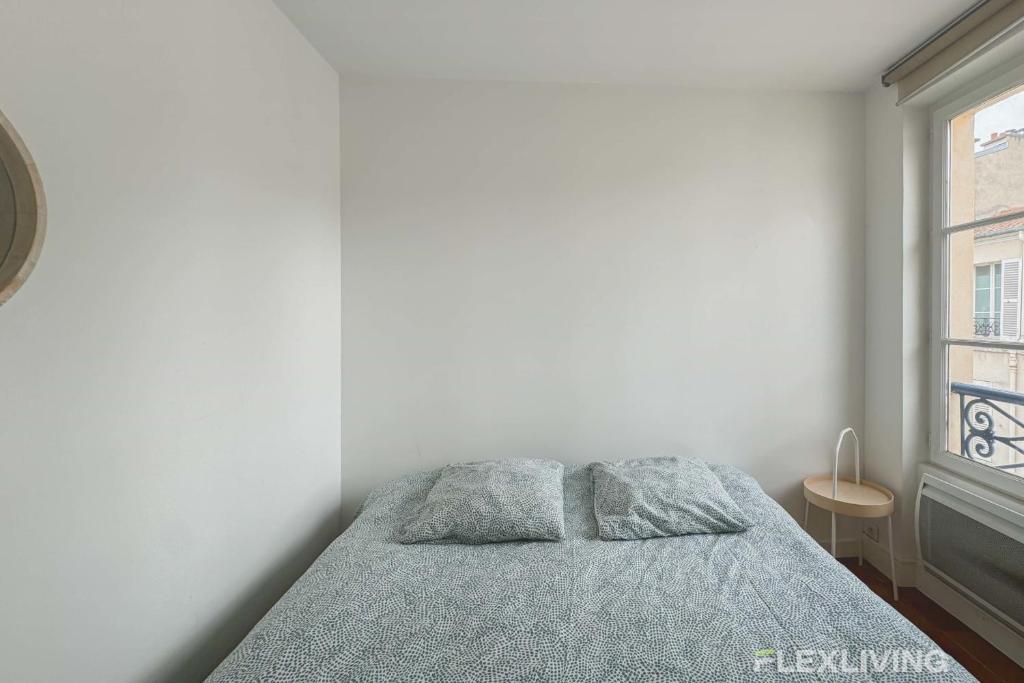 une chambre blanche avec un lit et une fenêtre dans l'établissement Flexliving - room - Augereau, à Paris