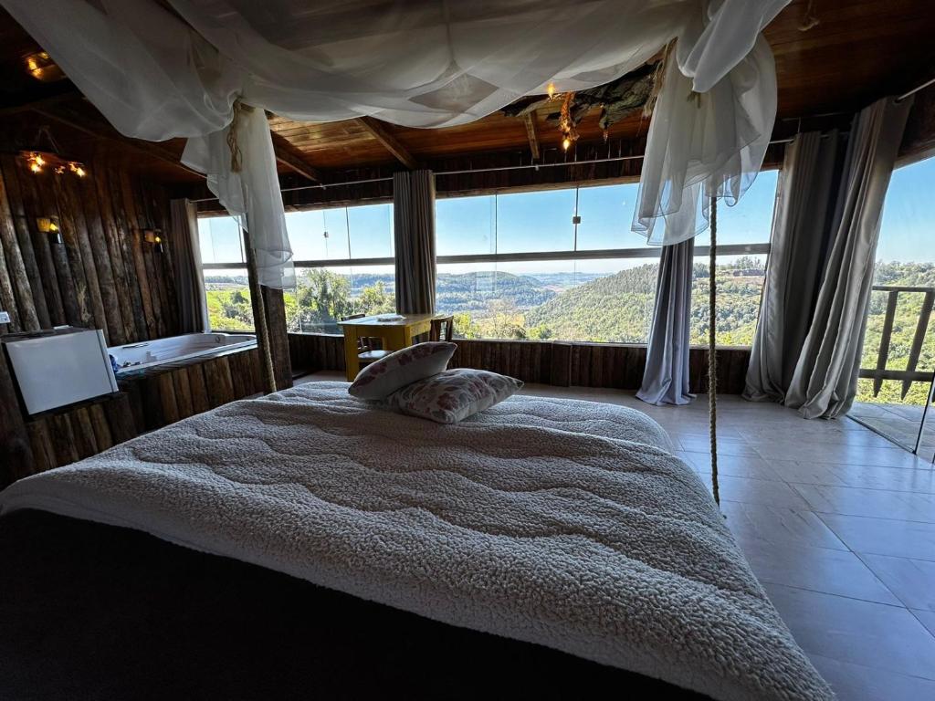a bedroom with a large bed with a large window at Pousada Vale de Luz FW in Frederico Westphalen