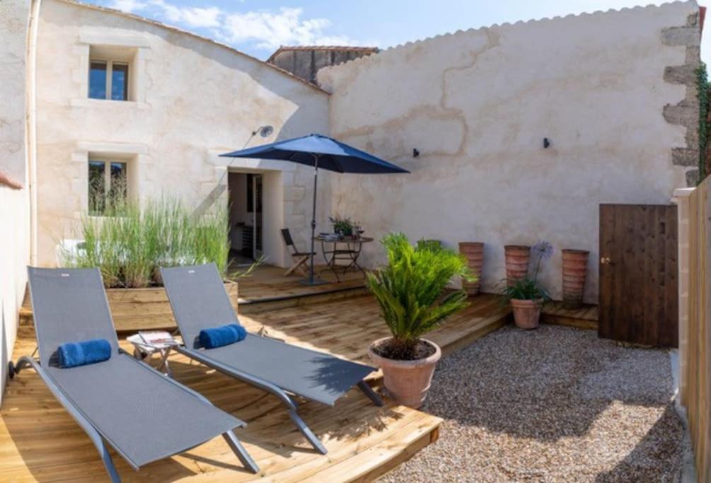 un patio avec deux chaises et un parasol dans l'établissement Charmant Atelier de la Fontaine, à Saint-Seurin-de-Prats