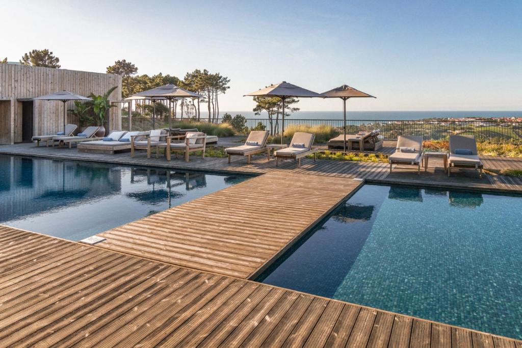 a pool with chairs and umbrellas on a house at Immerso Hotel, a Member of Design Hotels in Ericeira