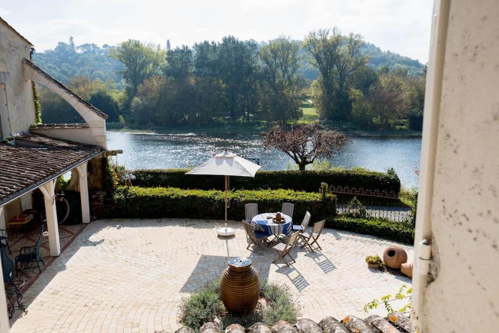un patio avec un parasol, une table et des chaises dans l'établissement Magnifique Maison de la Rivière, à Saint-Seurin-de-Prats