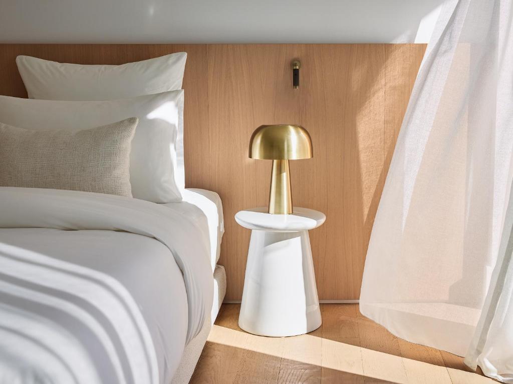 a bed with a gold lamp on a side table at The Roc Club, A Grecotel Hotel to Live in Athens