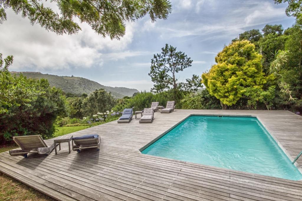 a swimming pool on a wooden deck with lounge chairs at Piesang Valley Lodge in Plettenberg Bay