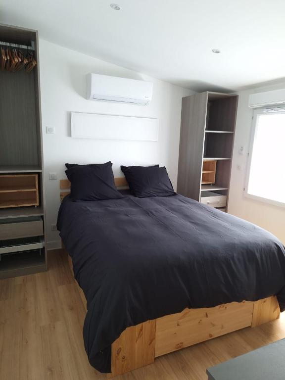 - une chambre avec un grand lit et des draps noirs dans l'établissement Le Loft Minimaliste, à Savigny-sur-Orge