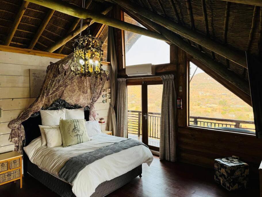 Un dormitorio con una cama grande con una lámpara de araña. en Breakaway Bushveld Mansion at Olifantsrivier ,Presidentsrus, en Botshabelo
