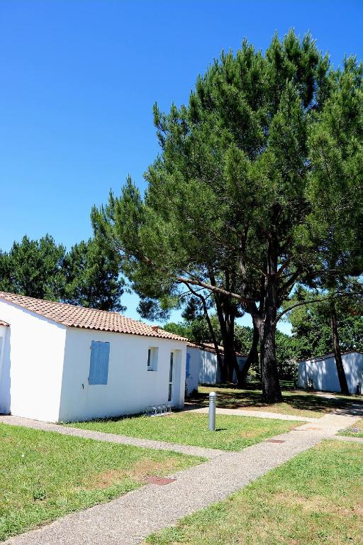 Un bâtiment blanc avec un arbre à côté dans l'établissement Charmante petite maison pour 4 personnes CDC FR90C10G, à Dolus-d'Oléron