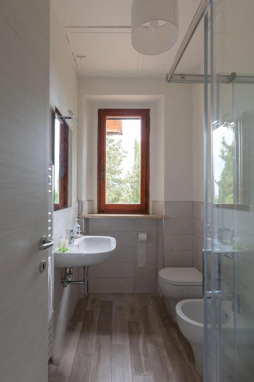łazienka z umywalką, toaletą i oknem w obiekcie Casalchino-Fattoria La Torre w mieście San Gimignano