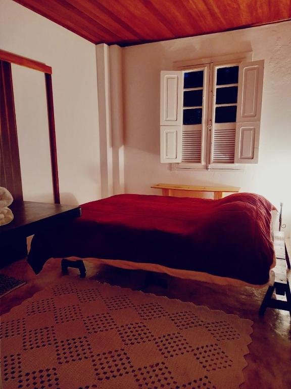 a bedroom with a red bed with a window at Casa da Áfrika - Suíte Jasmin in Itanhandu