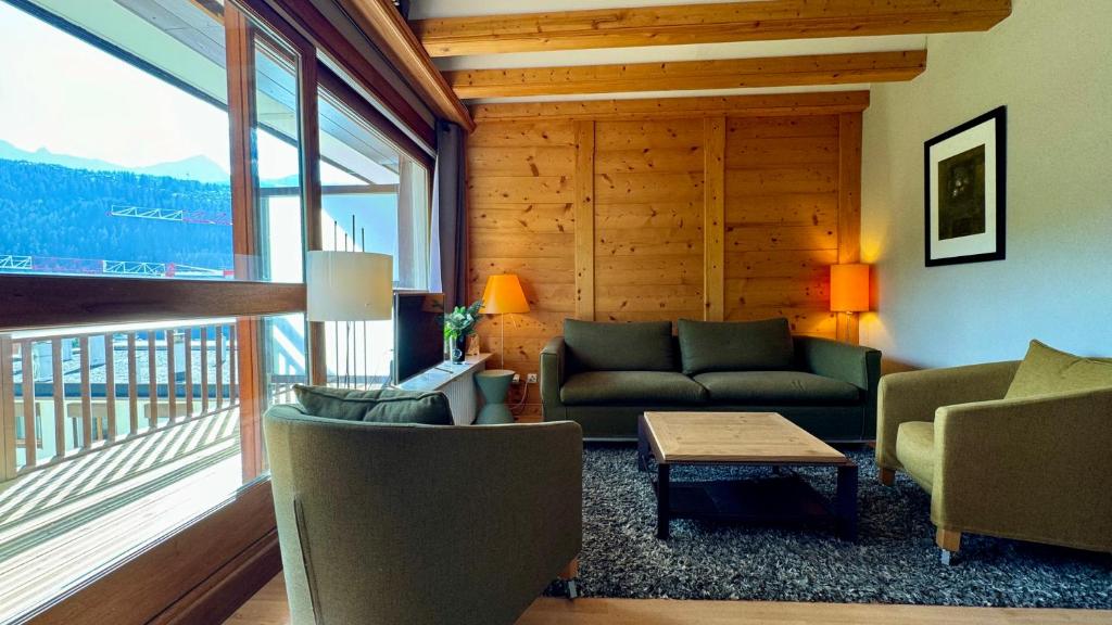 un salon avec un canapé et une grande fenêtre dans l'établissement Appt résidence 1650 ski aux pieds, à Courchevel