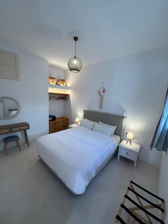 a white bedroom with a large bed and a table at Anemi KHORA in Mikonos