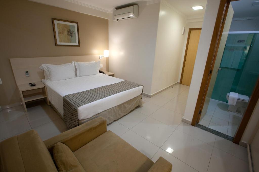 a hotel room with a bed and a couch at Oitis Hotel in Goiânia