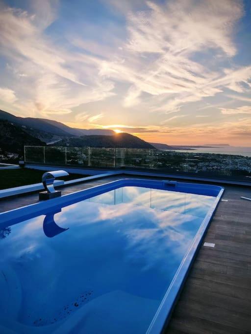 a swimming pool on top of a building with the sunset at Thea Villa Santa Marina in Malia