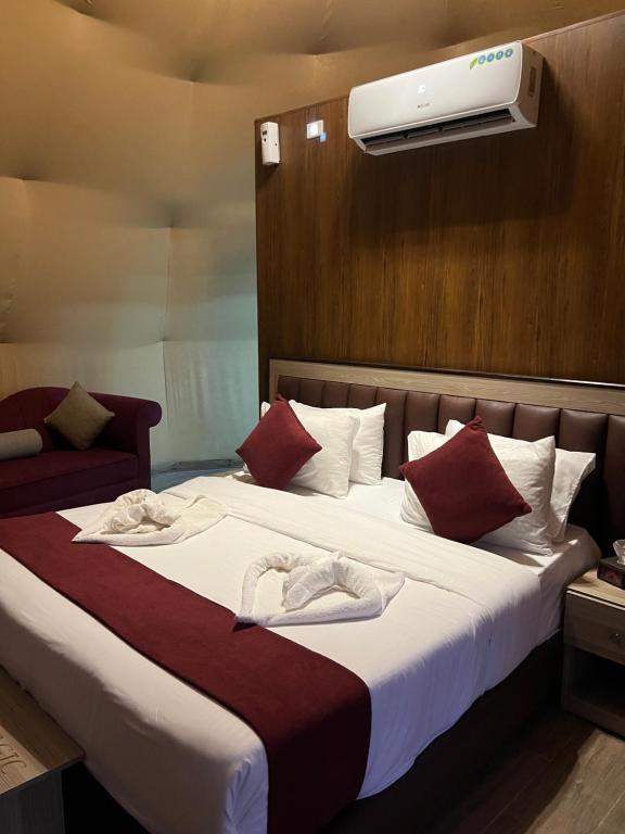 a bedroom with a large bed with a air conditioner on the wall at Wadi Rum Rose Luxury camp in Wadi Rum