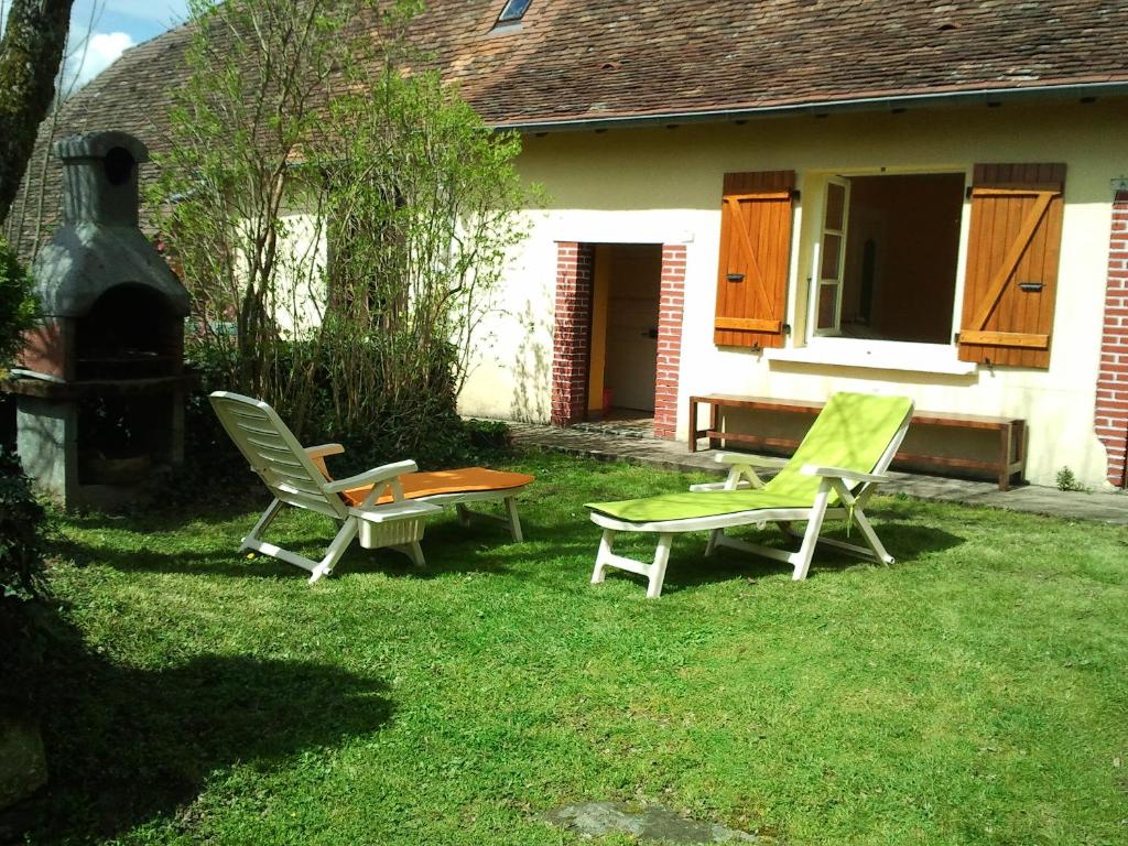 two chairs and a table in the yard of a house at Gite Des Croix Bancaud in Jumilhac-le-Grand