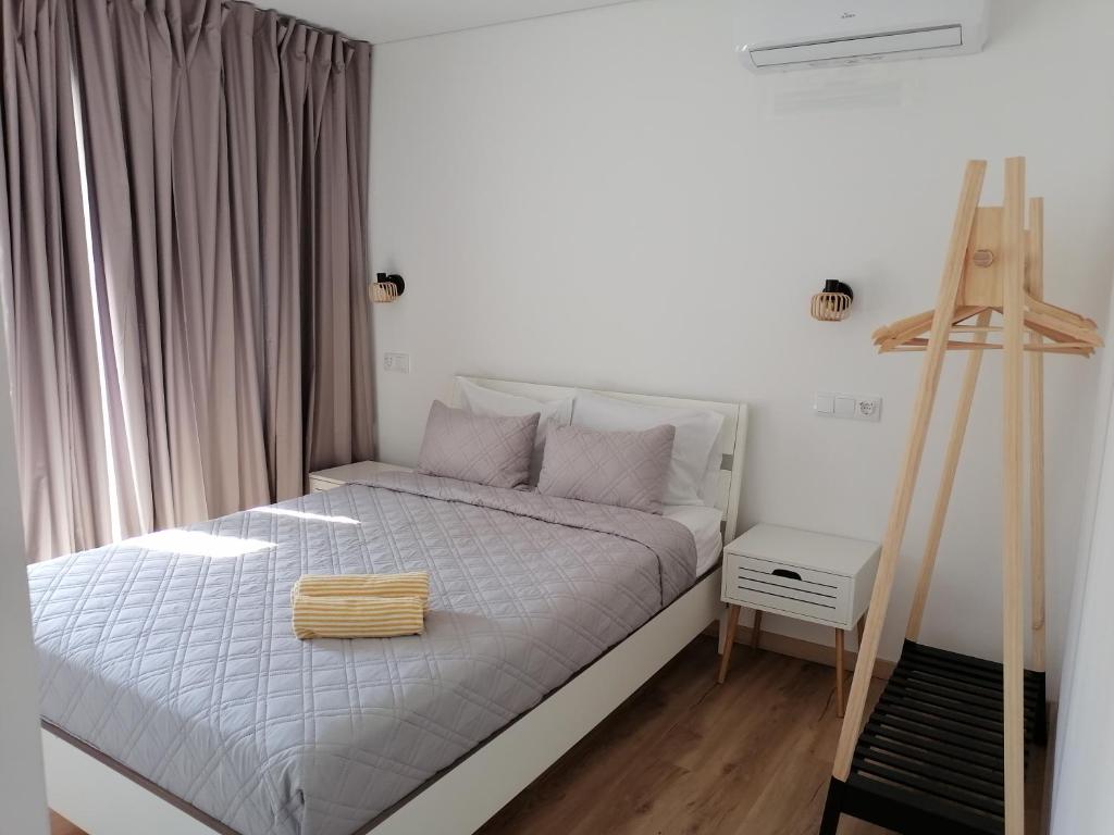 a bedroom with a white bed with a wooden ladder at Guest House Kaka in Maia