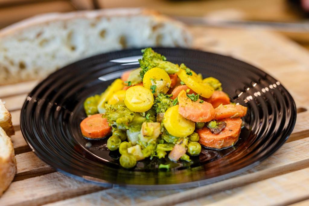 a black plate of food with vegetables on a table at Hotel Active Stadium in Lovosice
