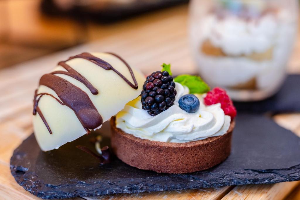 a dessert with whipped cream and berries on a black plate at Hotel Active Stadium in Lovosice