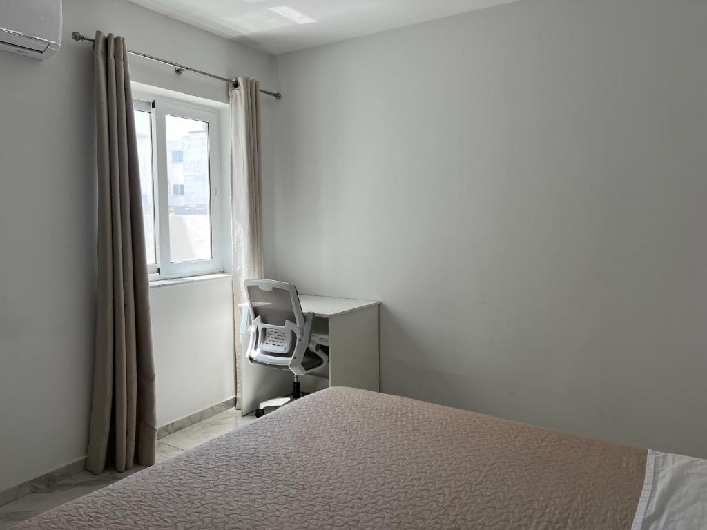 ein Schlafzimmer mit einem Bett, einem Schreibtisch und einem Fenster in der Unterkunft Faxxina in Is-Swieqi
