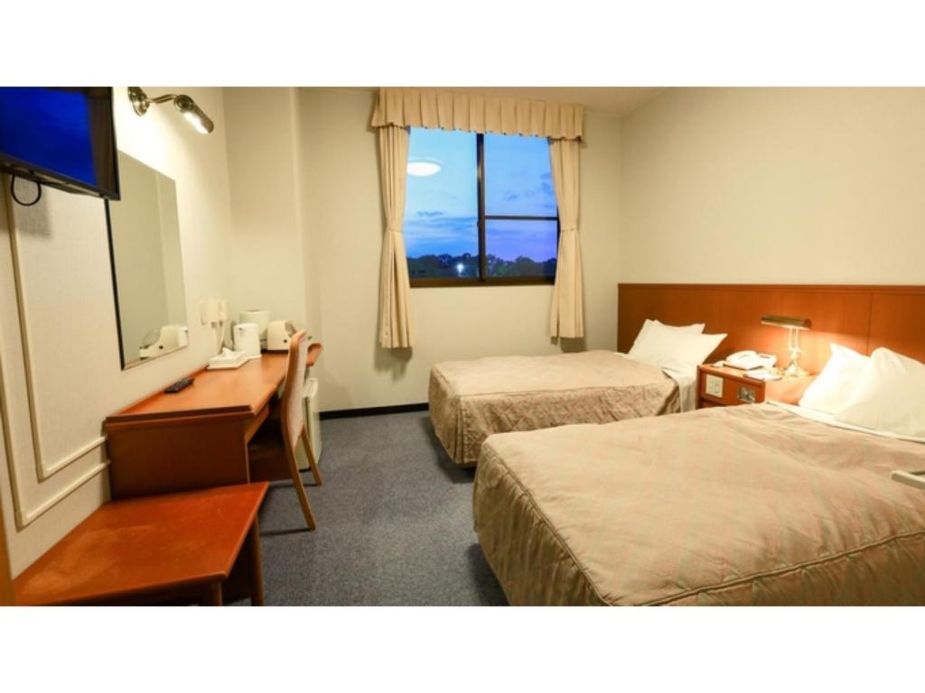 a hotel room with two beds and a desk and a window at Hill Hotel Sunpia Iga - Vacation STAY 66997v in Iga