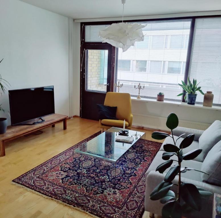 Una sala de estar con un sofá y una mesa de cristal. en Spacious Apartment in Kallio, en Helsinki
