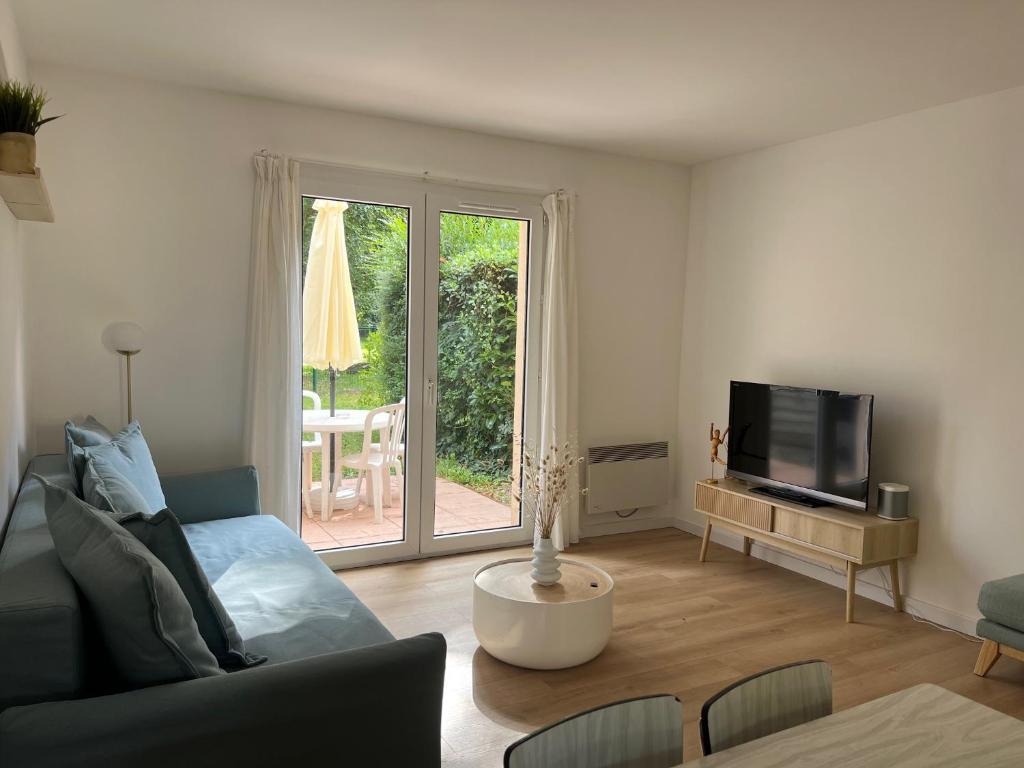 un salon avec un canapé et une télévision dans l'établissement Cottage Douillet 2 nuits minimum, à Ploemel